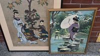 Two framed portraits: one with two Asian figures under a tree, and one of a woman in traditional dress with a parasol crossing stepping stones in a garden