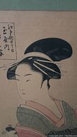 Close-up of the Geisha's head and shoulders with visible Japanese calligraphy above her in the print.
