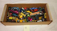 Box with a mass of assorted Matchbox vehicles of various types and colors, featuring many small die-cast toy cars and trucks.