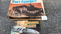Fort Apache playset box with plastic fort and toy figures, along with Battlestar Galactica game box visible.