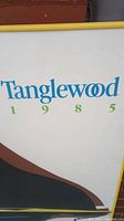 Close up image showing text 'Tanglewood 1985' in blue and green on white background from lithograph.