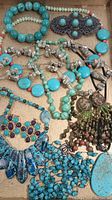 Overview of turquoise jewelry lot in wooden tray, showing bracelets, necklaces, earrings, and brooches.