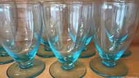 Close-up image showing six clear stemware glasses with electric blue bases arranged in two rows.