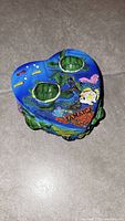 Top view of heart-shaped 3D jewelry box showing two green turtles, colorful fish, coral, and 'JAMAICA' text on the lid.