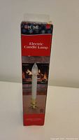 Front view of the box showing the product name Electric Candle Lamp with an image of the candle lamp and holiday themed background.