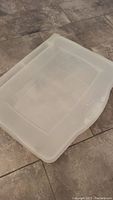 Full view of the large clear Rubbermaid plastic storage case showing the top with lid closed, visible surface scratches.