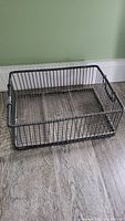 Full view of the large rectangular silver wire metal basket on wood floor.