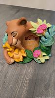 Front view of the 3D Lion King picture frame showing Simba and Nala hugging, with colorful foliage and flowers. The frame holds a 2-inch photo.