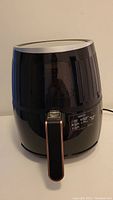 Front view of black Crux air fryer with handle and cylindrical shape.