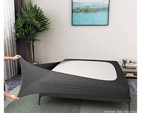 Box spring cover stretched over a bed frame and box spring, showing full coverage and fit.