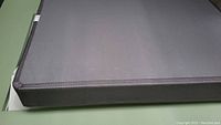 Gray fabric surface and edge corner of the box spring with neat stitching and border, showing clean condition.