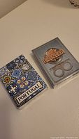 Two sealed decks of playing cards on a white surface. The Portugal deck shows classic tile patterns with the word PORTUGAL. The America's Most Wanted deck shows the logo with handcuffs.