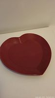 Red heart-shaped plate viewed slightly angled, showing full shape and glossy finish.