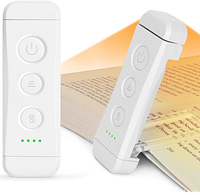 White portable book light shown clipped to a book edge illuminated with warm light and featuring three buttons.
