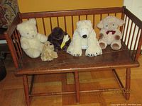 Antique wooden day bed with five plush animals displayed on it