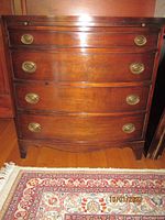 Front view of the vintage mahogany chest showing four drawers and brass hardware.