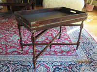 Photo of the assembled campaign table with removable tray on foldable base, showing dark wood and beaded trim.