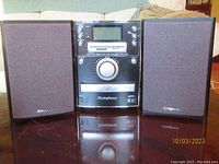 Full view of iSymphony compact disc memory card player/clock radio with two matching speakers, all black with iSymphony branding.