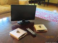 Element television on coffee table alongside remote control and two packaged antennas.