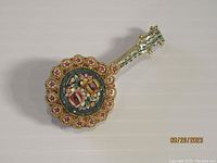 Photo of the vintage micro mosaic mandolin/guitar brooch showing the full front view, highlighting the floral and star designs on the rounded body.