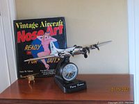 Photo showing the model airplane and the aircraft nose art book on table, with clear view of book title and airplane model details.