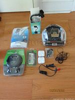 Full view of all items on floor including wireless headphones, smartphone mount, Sony Walkman, CD player, screen guard, and earbuds.