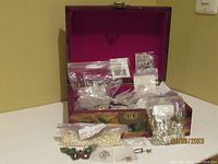 Overall lot inside decorative box showing jewelry making supplies including bags with beads, pendants, and earring parts