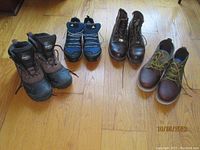 All four pairs of men's footwear arranged on wooden floor showing Clarks, Adidas Gore-Tex, Chippewa, and Itasca boots.