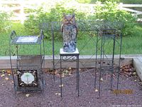 Overview of all four metal plant stands and resin owl on one stand, showing scale and weathered condition.