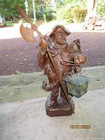 Front view of the wooden nightwatchman figure holding a halberd and lantern, showing detailed carving and the lantern attached to the figure.