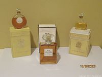Three perfume bottles: center Chanel No 5 with box, left and right Nina Ricci L'Air du Temps with boxes.