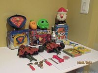 Lot overview showing all items: Superman desk clock on box, Nintendo 64 Pokemon Stadium empty box, vintage Frosty the Snowman in original box, two Halloween dolls, squeeze toys, and Knowledge Card packs.