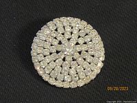 Front view of clear rhinestone brooch, 2 inch diameter, showing circular layered rhinestone pattern with central larger clear rhinestone