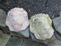 View of two lion head stone planters/wall plaques side by side showing front detail and texture