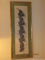 Full frontal view of the framed temple rubbing showing the vertical arrangement of traditional Thai figures on textured rice paper with a green silk border and bamboo style frame.