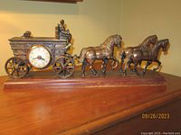 Full side view of the vintage United Clock Co. 4 horse stagecoach mantel clock on wooden base.