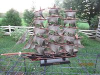 Full view of the Cutty Sark model ship showing multiple masts and sails with an outdoor background.