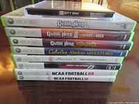 Stack of 8 Xbox 360 games and 1 PC game with visible titles and cases stacked horizontally
