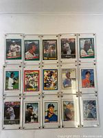 Photo of 15 MLB baseball player trading cards, front side, sleeved in plastic holders showing various players in batting, pitching, and posing stances.