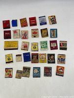 Photo showing 31 assorted vintage advertising matchbook covers and match boxes, displaying various colors, logos, and wear conditions.