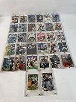 Front view of 32 assorted NFL football player collectible trading cards laid out in protective sleeves, showing various players in action and poses.
