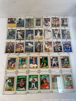 Photo showing the front side of 33 assorted MLB baseball player collectible trading cards arranged in rows, all in protective plastic sleeves.