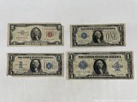 Front view of 4 assorted vintage US dollar bills, 1 two-dollar bill and 3 one-dollar bills, worn with age.