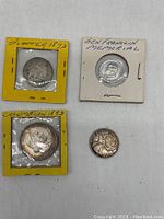 Front view of four coins including 2 Mcts 1873, Colombian 1893, Ben Franklin Memorial, and a smaller coin.