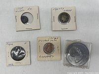 Top view of 5 assorted coins including 1868 nickel 3-cent, Betty Lady coin, 1864 England 1-cent, 1949 copper double mint coin, and a larger coin with British National Defence Fund text.