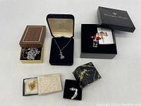Five assorted jewelry pieces including pendants, brooches and a ring in display boxes.