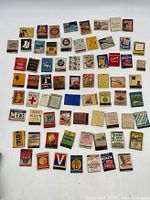 Overview photo showing 70 assorted vintage advertising matchbook covers and match boxes arranged in rows.