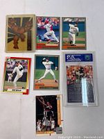 Top front view of all 7 cards arranged in two rows: 1 Comics (Thing character), 3 baseball cards, 1 NBA basketball card, 1 graded football card encased, 1 additional baseball card.