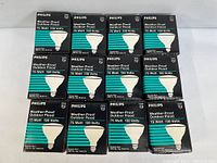 Thumbnail view showing 12 individual Philips branded boxes of outdoor flood light bulbs stacked in rows, all labeled for 75 watt 130 volts.