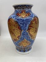 Front view showing the vase's intricate phoenix and floral gold details on a blue background.